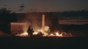 Two people standing in front of a fire at night