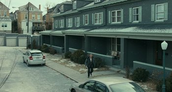 Movie still from “A Man Called Otto” (2022), directed by Marc Forster – A man walking down the sidewalk in front of a row of houses; Extreme Wide shot, High angle