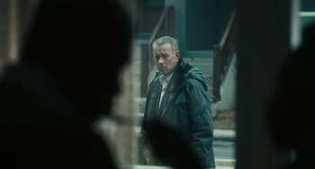 Movie still from “A Man Called Otto” (2022), directed by Marc Forster – A man wearing a coat and a jacket walking down a street; Medium shot, Over the shoulder angle