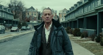Movie still from “A Man Called Otto” (2022), directed by Marc Forster – A man standing on the side of the road in front of houses; Medium shot, Low angle