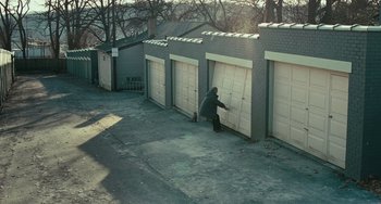 Movie still from “A Man Called Otto” (2022), directed by Marc Forster – A man in a jacket and hat is opening a garage door; Extreme Wide shot, High angle