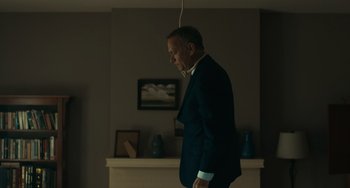 Movie still from “A Man Called Otto” (2022), directed by Marc Forster – A man in a suit and tie standing next to a fire place; Medium shot, Low angle