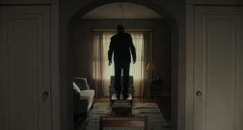 Movie still from “A Man Called Otto” (2022), directed by Marc Forster – A man standing in front of a window in a living room; Wide shot, Low angle