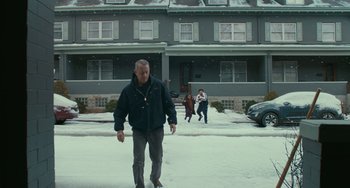 Movie still from “A Man Called Otto” (2022), directed by Marc Forster – A man is walking in the snow while two other people are walking in front of a house; Wide shot, Low angle