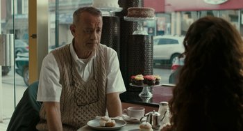 Movie still from “A Man Called Otto” (2022), directed by Marc Forster – An older man sitting in front of a plate of cupcakes; Medium shot, Over the shoulder angle