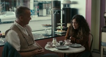 Movie still from “A Man Called Otto” (2022), directed by Marc Forster – A man and a woman sitting at a table in front of cakes; Medium shot, Over the shoulder angle
