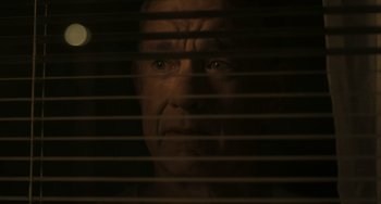 Movie still from “A Man Called Otto” (2022), directed by Marc Forster – A man looking through a window blinds at night; Close Up shot, Low angle