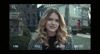 Movie still from “A Man Called Otto” (2022), directed by Marc Forster – A woman with long blonde hair standing in front of a brick building; Close Up shot, Over the shoulder angle