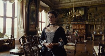 Movie still from “The Favourite” (2018), directed by Yorgos Lanthimos – A woman dressed in period clothing standing in an ornate room; Medium shot, Low angle