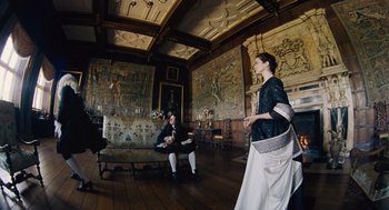 Movie still from “The Favourite” (2018), directed by Yorgos Lanthimos – Two people are sitting on a couch in a room; Wide shot, High angle