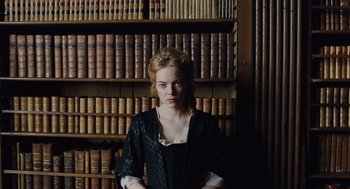 Movie still from “The Favourite” (2018), directed by Yorgos Lanthimos – A woman standing in front of a book shelf; Medium shot, Low angle
