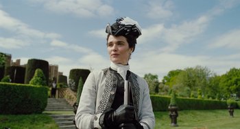 Movie still from “The Favourite” (2018), directed by Yorgos Lanthimos – A woman in a white jacket and a black hat; Medium shot, Low angle