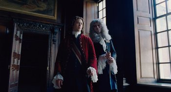 Movie still from “The Favourite” (2018), directed by Yorgos Lanthimos – Two men dressed in period costumes stand in front of a fireplace; Medium shot, Low angle