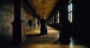 Movie still from “The Favourite” (2018), directed by Yorgos Lanthimos – A man in a long black coat in an ornate room; Wide shot, Low angle