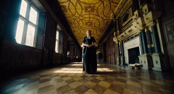 Movie still from “The Favourite” (2018), directed by Yorgos Lanthimos – A woman in a black dress standing in a room; Wide shot, Low angle