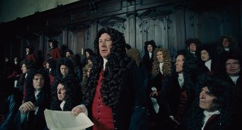 Movie still from “The Favourite” (2018), directed by Yorgos Lanthimos – An old man in a wig is standing in front of a group of people; Medium shot, Over the shoulder angle
