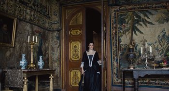 Movie still from “The Favourite” (2018), directed by Yorgos Lanthimos – A woman dressed in period clothing standing in front of a door; Wide shot, High angle