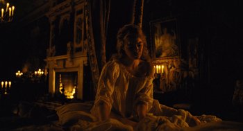 Movie still from “The Favourite” (2018), directed by Yorgos Lanthimos – A woman sitting on a bed in front of a fire place; Wide shot, High angle