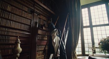 Movie still from “The Favourite” (2018), directed by Yorgos Lanthimos – A woman standing on top of a ladder in front of a book shelf; Medium shot, Low angle