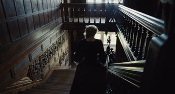 Movie still from “The Favourite” (2018), directed by Yorgos Lanthimos – A woman walking down a wooden stair case; Wide shot, High angle