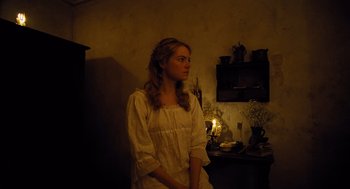 Movie still from “The Favourite” (2018), directed by Yorgos Lanthimos – A young woman sitting in front of a candle lit fireplace; Medium shot, Over the shoulder angle