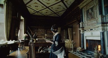 Movie still from “The Favourite” (2018), directed by Yorgos Lanthimos – A woman dressed in period clothing reading a book; Wide shot, Low angle