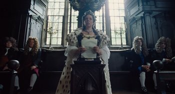 Movie still from “The Favourite” (2018), directed by Yorgos Lanthimos – A woman wearing a crown and holding a sheet of paper in front of a window; Medium shot, Low angle