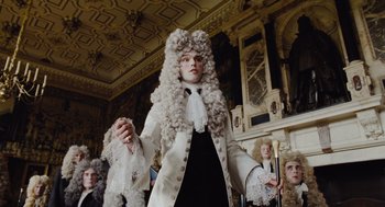 Movie still from “The Favourite” (2018), directed by Yorgos Lanthimos – A man in a white wig standing in front of a group of people; Medium shot, Low angle