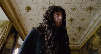 Movie still from “The Favourite” (2018), directed by Yorgos Lanthimos – A person with long hair and a wig on; Medium shot, Over the shoulder angle