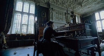 Movie still from “The Favourite” (2018), directed by Yorgos Lanthimos – A woman sitting at a piano in a room with ornate ceilings; Wide shot, Low angle