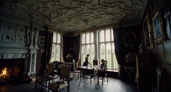 Movie still from “The Favourite” (2018), directed by Yorgos Lanthimos – Two people sitting at a table in front of a large window; Wide shot, Low angle