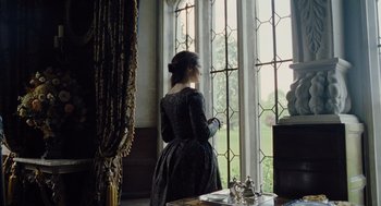 Movie still from “The Favourite” (2018), directed by Yorgos Lanthimos – A woman standing in front of a large window; Medium shot, Low angle