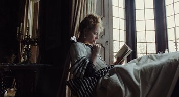 Movie still from “The Favourite” (2018), directed by Yorgos Lanthimos – A woman sitting in front of a window reading a book; Medium shot, Low angle
