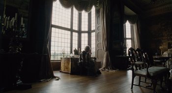 Movie still from “The Favourite” (2018), directed by Yorgos Lanthimos – A person sitting in a room with a large window; Wide shot, High angle