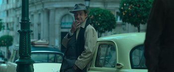 A man smoking a cigarette while leaning on a car