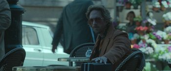 A man sitting at an outdoor table holding a briefcase