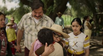 Movie still from “A Million Miles Away” (2023), directed by Alejandra Márquez Abella – A man holding a young girl in a straw hat; Medium shot, Over the shoulder angle