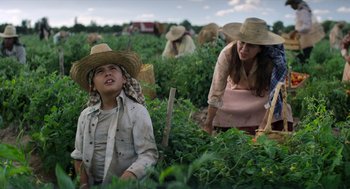 Movie still from “A Million Miles Away” (2023), directed by Alejandra Márquez Abella – Two women and a boy working in a field of tomatoes; Medium shot, Low angle