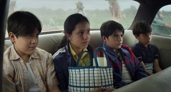 Movie still from “A Million Miles Away” (2023), directed by Alejandra Márquez Abella – A group of people sitting in the back of a car; Medium shot, Low angle