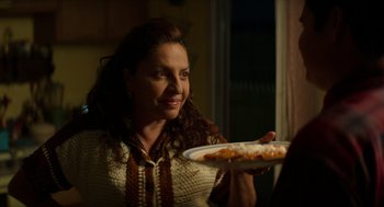 Movie still from “A Million Miles Away” (2023), directed by Alejandra Márquez Abella – A woman holding a plate of pizza in her hand; Close Up shot, Over the shoulder angle