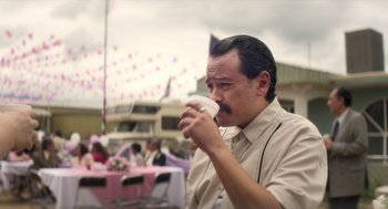 Movie still from “A Million Miles Away” (2023), directed by Alejandra Márquez Abella – A man drinking a cup of coffee at an outdoor event; Close Up shot, Over the shoulder angle