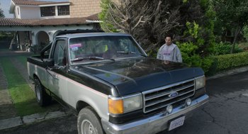 Movie still from “A Million Miles Away” (2023), directed by Alejandra Márquez Abella – A man standing in front of an old truck; Wide shot, High angle