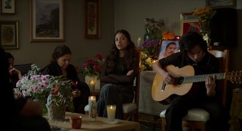 Movie still from “A Million Miles Away” (2023), directed by Alejandra Márquez Abella – A group of people sitting around a living room; Wide shot, High angle