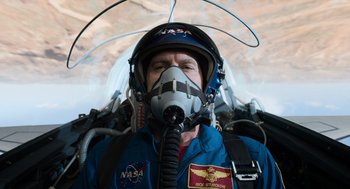 Movie still from “A Million Miles Away” (2023), directed by Alejandra Márquez Abella – A man wearing a space suit and a helmet; Medium shot, Overhead angle