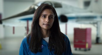 Movie still from “A Million Miles Away” (2023), directed by Alejandra Márquez Abella – A woman in a blue jacket standing in front of a plane; Close Up shot, Low angle