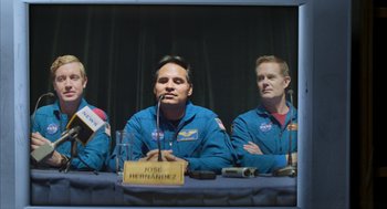 Movie still from “A Million Miles Away” (2023), directed by Alejandra Márquez Abella – Two men are sitting in front of microphones at a press conference; Medium shot, Overhead angle