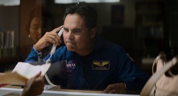 Movie still from “A Million Miles Away” (2023), directed by Alejandra Márquez Abella – A man sitting at a table talking on a phone; Medium shot, Over the shoulder angle