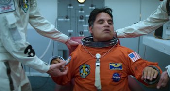 Movie still from “A Million Miles Away” (2023), directed by Alejandra Márquez Abella – A man in an orange space suit is being fitted for a space suit; Medium shot, Low angle