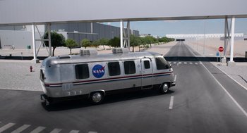 Movie still from “A Million Miles Away” (2023), directed by Alejandra Márquez Abella – A nasa bus driving down a street near a bridge; Wide shot, High angle