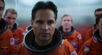 Movie still from “A Million Miles Away” (2023), directed by Alejandra Márquez Abella – A man in an orange space suit is looking at the camera; Close Up shot, Low angle